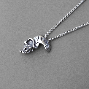 Close-up of retro skull pendant with hollow cross-section on grey leather texture