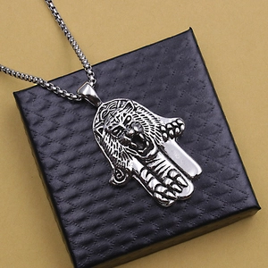 Close-up of vintage punk tiger Hamsa hand pendant necklace on black jewelry box