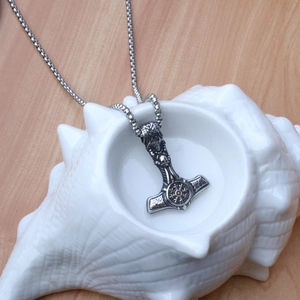 Detail of Viking Mjölnir pendant with runes and skull inside a decorative seashell