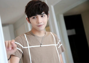 Close-up of a silver dumbbell pendant necklace worn by a model in a striped t-shirt