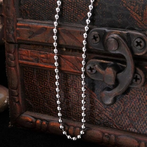 Polished silver beaded necklace chain with metallic luster on vintage wooden background