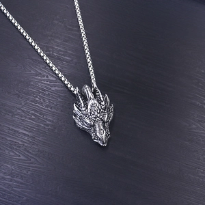 Detailed close-up of a stainless steel dragon head pendant with silver box chain necklace