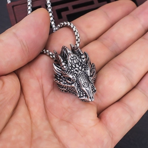 Detailed close-up of a vintage silver dragon head pendant held in hand for scale