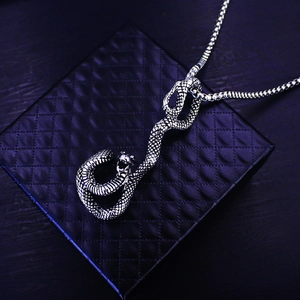 Close-up of vintage steel snake pendant with detailed scales on a black leather box