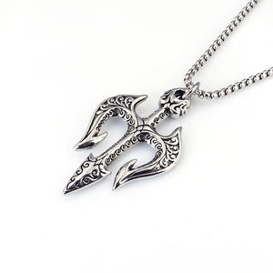 Macro detail of retro trident pendant with embossed patterns on a silver box chain