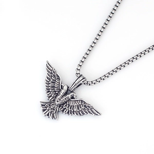 Dettaglio del ciondolo aquila vintage con piume testurizzate su una collana a catena box