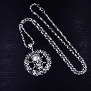 Détail macro du pendentif tête de mort celtique argenté avec chaîne box sur bois noir