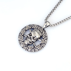 Détail d'un pendentif crâne punk vintage avec nœud celtique sur une chaîne à maillons