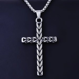 Close-up of vintage stainless steel cross pendant with wheat pattern on a box chain