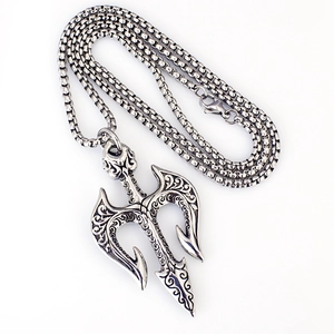 Macro view of vintage trident pendant with intricate scrollwork on a silver box chain
