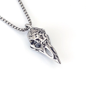 Macro detail of Nordic Viking bird skull pendant with intricate engravings on box chain