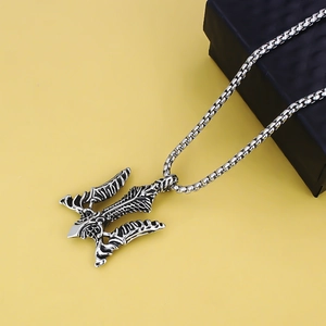 Vintage stainless steel trident pendant necklace with engraved texture on yellow backdrop
