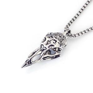 Detailed view of the antique silver raven skull pendant with ornate scroll carvings