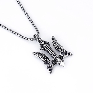 Macro detail of vintage silver trident pendant with intricate feather engravings on box chain