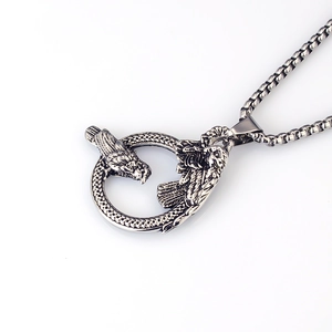 Detail of vintage stainless steel round pendant with dragon totem and box chain