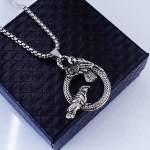 Detailed view of hollow ring pendant with two carved crows on a round box chain
