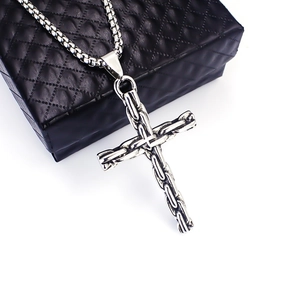 Vue macro d'un pendentif croix en acier inoxydable avec texture de chaîne tressée détaillée