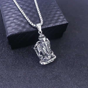 Dettaglio macro del ciondolo Ganesha in argento su catena box su sfondo scuro testurizzato