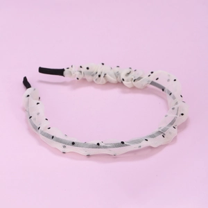 Détail d'un serre-tête en mousseline blanche à pois noirs avec texture en maille