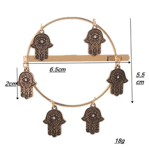 Detailed view of golden hamsa hand charms on a geometric ring hair clip with measurements