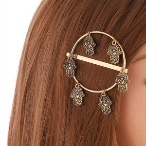 Dettaglio del fermaglio vintage dorato con sei ciondoli Mano di Fatima e strass