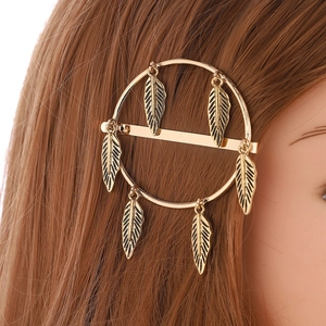 Dettaglio di un fermaglio per capelli vintage dorato con sei ciondoli a forma di piuma