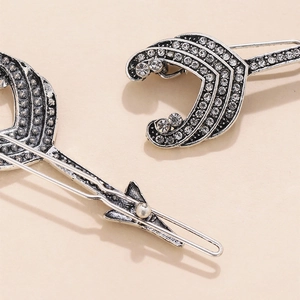 Gros plan de deux barrettes argentées avec design évidé en forme de C et strass
