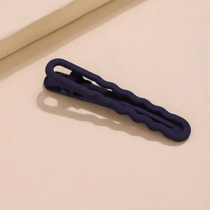 Navy blue matte U-shaped metal hair clip with hollow wave design on a textured surface