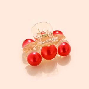 Detailed close-up of a mini hair claw clip with glossy red pearls and clear acrylic body