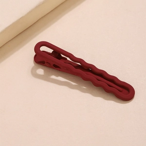 Detail of red matte wave hair clip with a stylish textured finish on a beige background