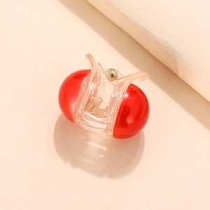 Detail view of transparent claw clip with glossy red spherical accents and metal spring