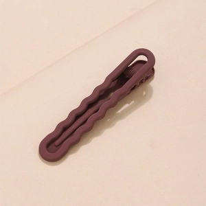 Detail view of wavy matte brown hair clip with elegant minimalist finish on light background