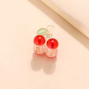 Elegant cherry hair claw clip with glossy red pearls and green leaf on beige background