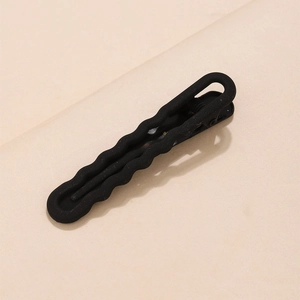 Detail of matte black U-shaped duckbill hair clip with elegant wave edge and oval cutout