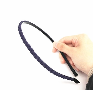 Dettaglio di un cerchietto intrecciato in pelle scamosciata viola scuro con telaio nero