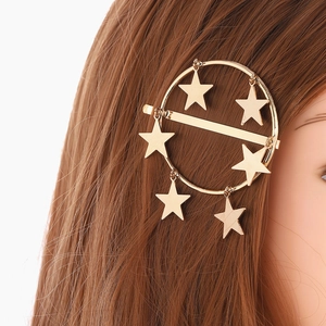 Dettaglio di un fermaglio per capelli dorato circolare con ciondoli a stella