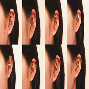 Collage of eight gold ear crawlers with zircon butterfly, cross, and leaf motifs