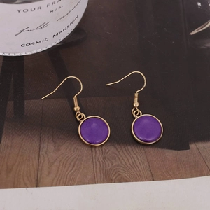 Detalle de pendientes redondos morados con ganchos dorados sobre fondo de estilo vintage