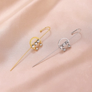 Macro view of gold and silver rhinestone ear wraps on soft pink silk background