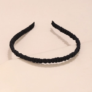 Detailed close-up of a black pleated fabric headband showing soft texture and elastic design