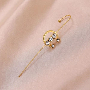 Close-up of gold ear crawler with sparkling rhinestones on champagne satin fabric