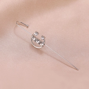 Detailed view of silver-plated ear crawler with five sparkling crystals on silk fabric