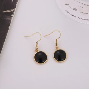 Detalle de pendientes redondos de esmalte negro con ganchos dorados minimalistas