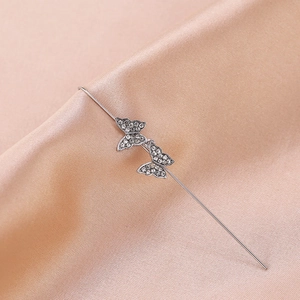 Detail of silver butterfly ear crawler with rhinestones on champagne silk background