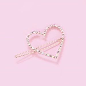 Detail of a gold heart hair clip with colorful AB rhinestones on a pink background