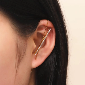 Detail shot of a minimalist gold crawler earring with white zircons on a model's ear