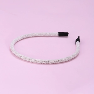Detailed top view of a white beaded fashion headband on a solid pink background
