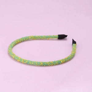 Detail of beaded headband with yellow and green sequins and black grosgrain ribbon ends
