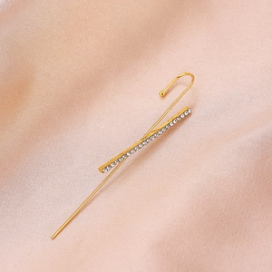 Detail view of a golden lightning-shaped ear crawler with white rhinestones on pink silk