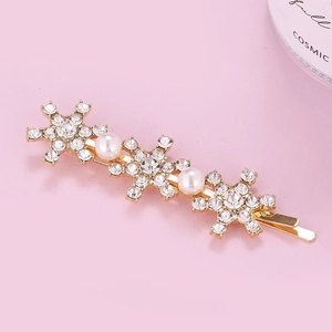 Detailed view of golden snowflake hair clip with shiny rhinestones and white pearls